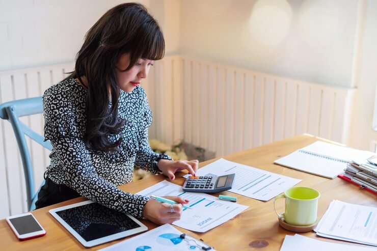 Person planning a monthly budget with a notebook calculator and household expenses