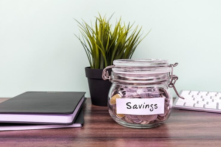 Simple ways to save more money with a budget notebook, savings jar, calculator and financial planning tools.