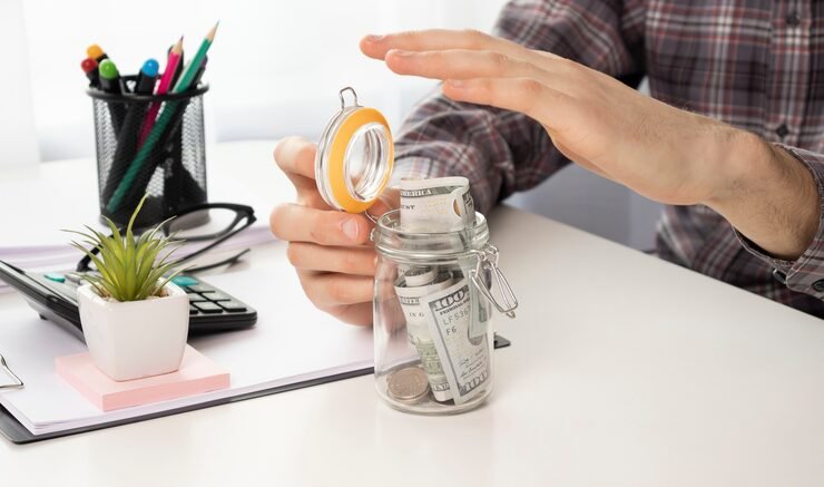 Simple ways to save more money with a budget notebook, savings jar, calculator and financial planning tools.